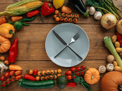Knife and Fork on a Ceramic Plate Surrounded by Assorted Vegetables Knife and Fork on a Ceramic Plate Surrounded by Assorted Vegetables<br />